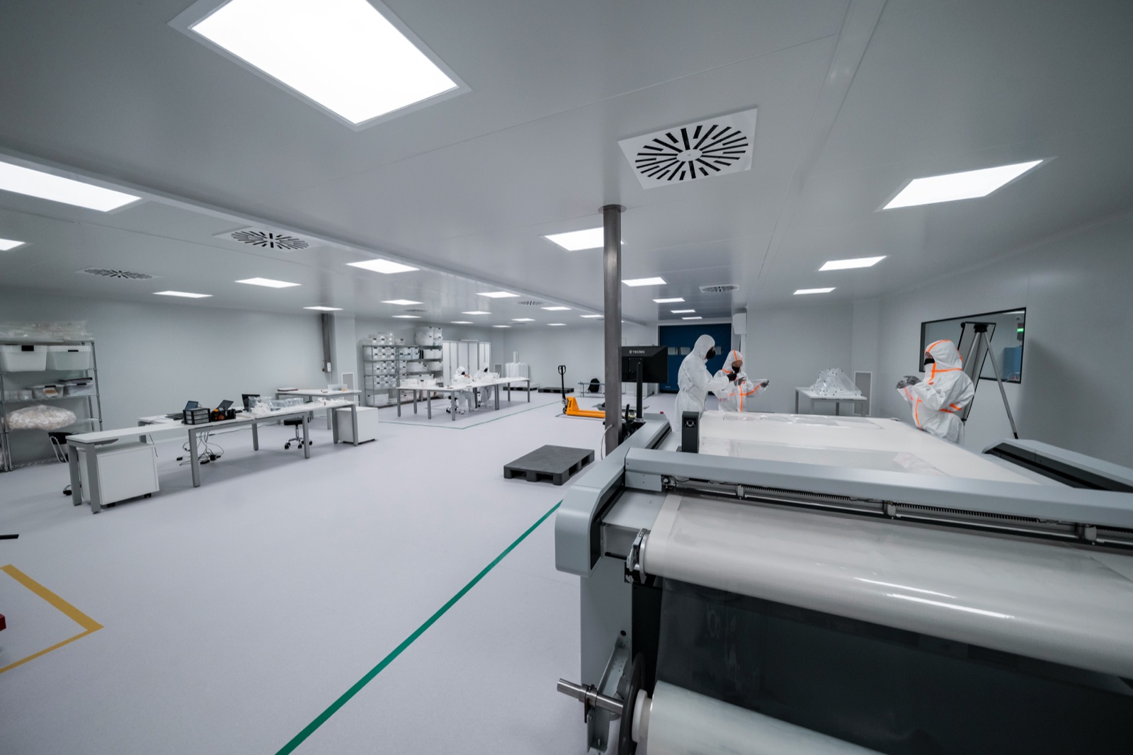 Cleanroom facility with workers in white protective suits for sterile medical device manufacturing