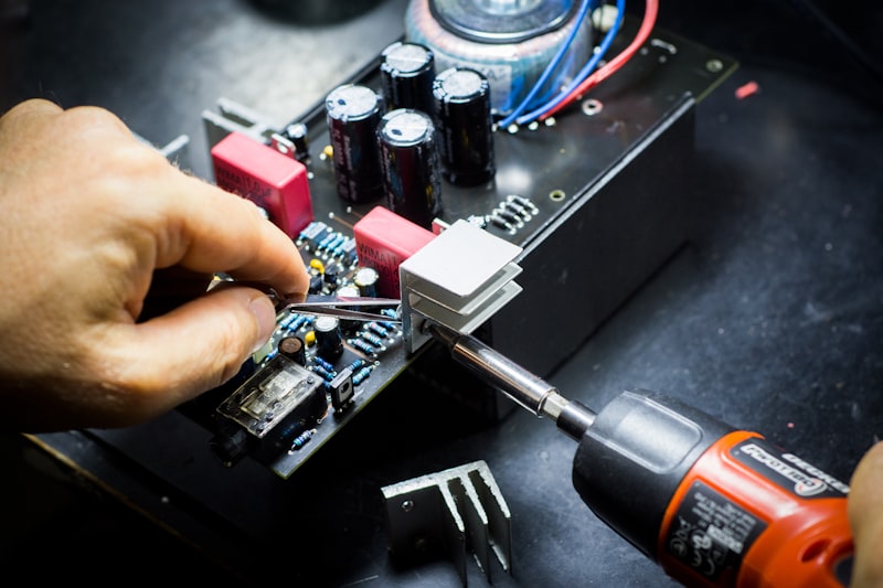 Hands assembling circuit board components with precision tool for Uni-Weld™ UV component staking and wire tacking