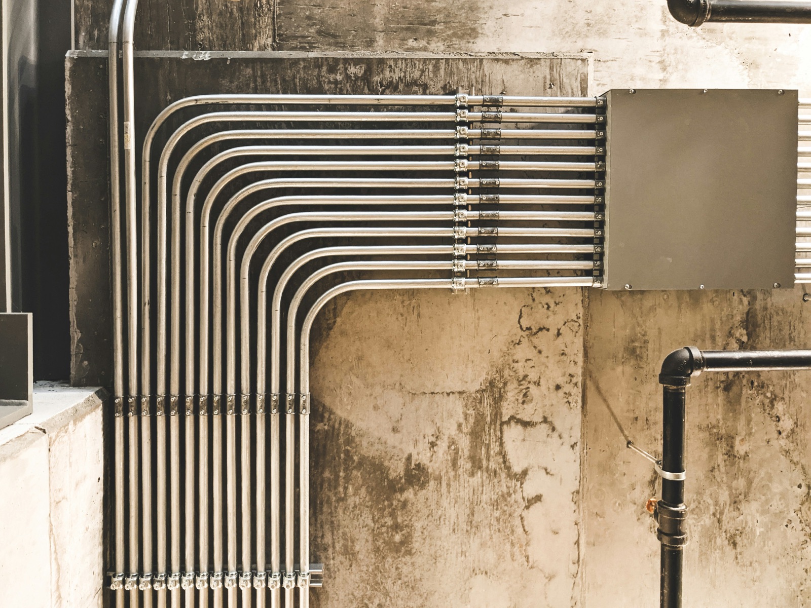 Industrial conduit and pipe bundle along concrete wall for Pyra-Sil™ UV silicone form-in-place gasket FIPG sealing